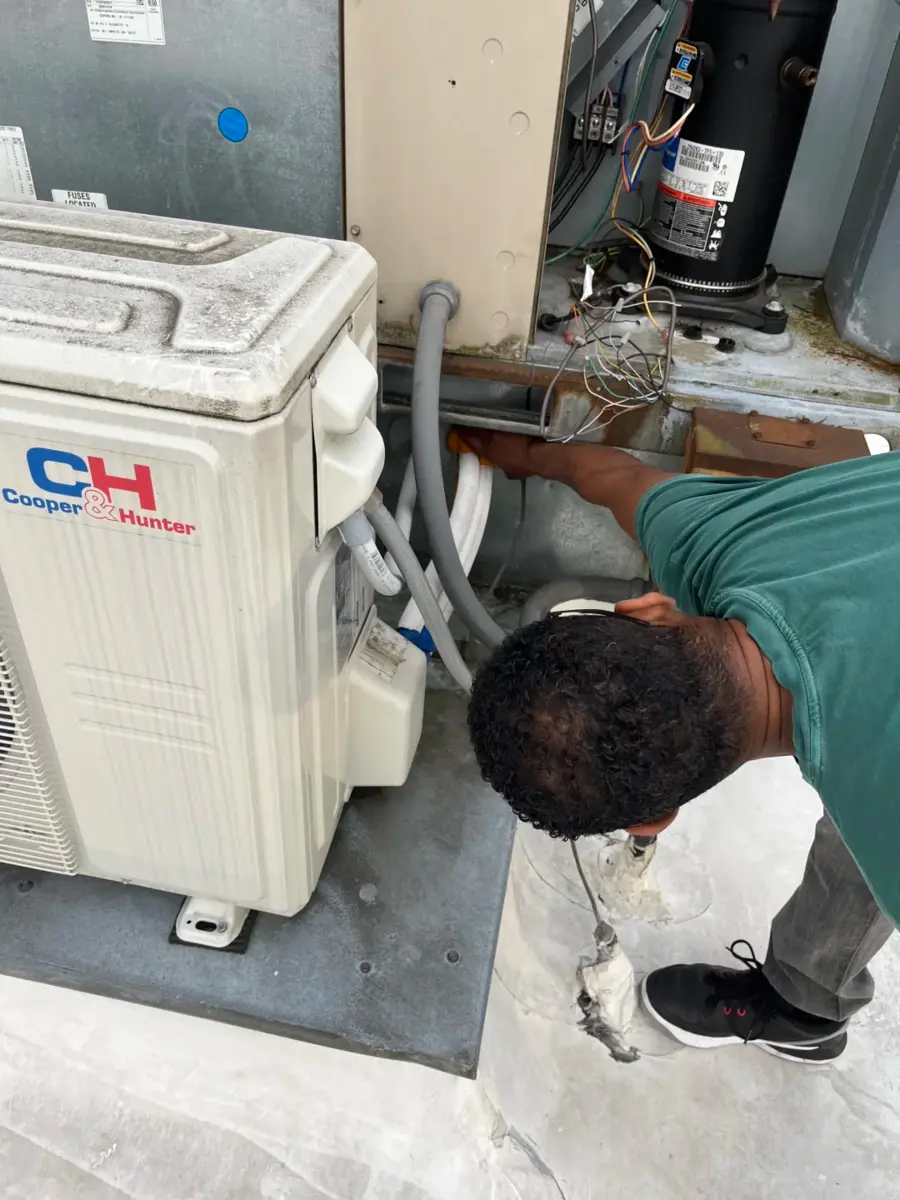Technician inspecting open outdoor air conditioning equipment