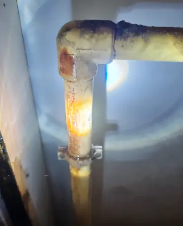 Aged pipe connection with visible staining and deterioration