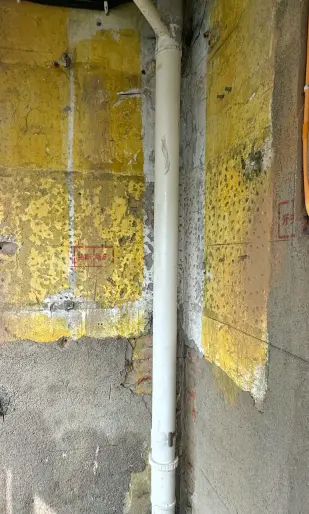Vertical replacement pipework beside a wall